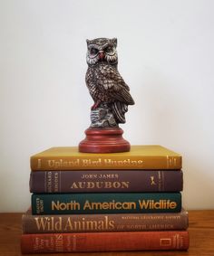 three books stacked on top of each other with an owl figurine atop them