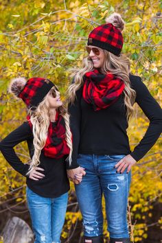 two women wearing plaid hats and scarves standing next to each other in front of trees