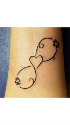 a small tattoo on the ankle of a woman's foot with two cats and paw prints