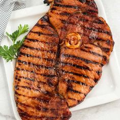 grilled meat on a white plate with parsley