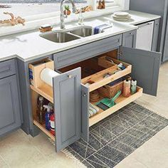 a kitchen with gray cabinets and white counter tops, an open cabinet door is in front of the sink