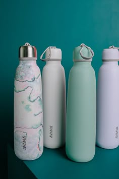 three different styles of water bottles sitting next to each other on a blue surface,