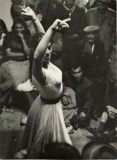 a black and white photo of a woman dancing in front of a group of people