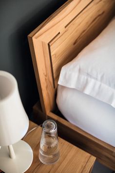 a bed with a wooden headboard and night stand next to a lamp on a nightstand