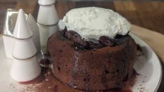 a chocolate cake on a plate with whipped cream and other dessert items around it, sitting on a wooden table