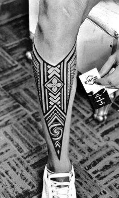 a black and white photo of a person's leg with an intricate tattoo on it