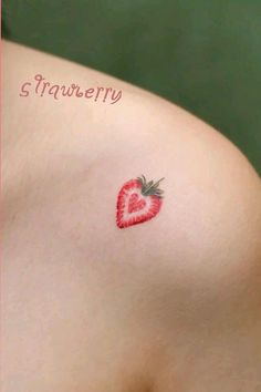 a small strawberry tattoo on the back of a woman's left shoulder and chest