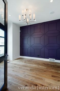 an empty room with wood floors and purple walls