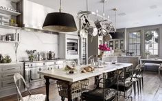 a large kitchen with lots of counter space and hanging lights above the dining room table