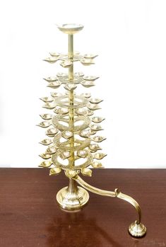 a brass candle holder with many candles on it's stand, sitting on a wooden table