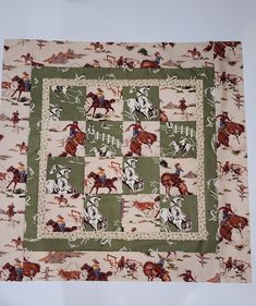 a quilted square with horses and jockeys on the same fabric as it sits on a table