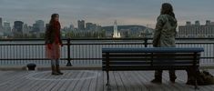 two people sitting on a bench looking at the city