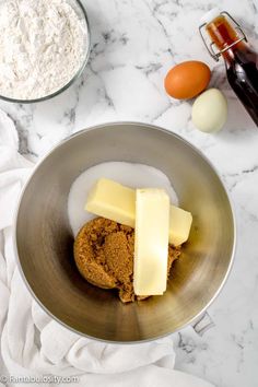 ingredients for making cookies in a bowl on a marble counter top with flour, butter and eggs