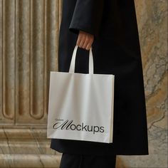 a person carrying a white bag with the word mockup on it