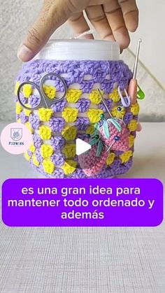 someone is holding a crocheted container with scissors and other items in it that are attached to the lid