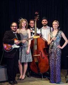 a group of people standing next to each other in front of a guitar and bass