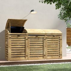 a large wooden storage unit sitting on top of a grass covered field next to a tree