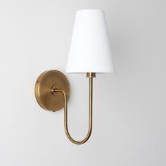 a wall light with a white shade on it's side and a gold arm