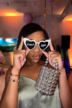 a woman holding up two heart shaped sunglasses with the word say so written on them