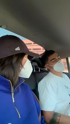 two people sitting in a car wearing face masks