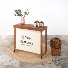 an empty kombucha stand with bottles on it and a plant next to it