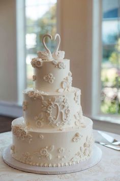 a three tiered wedding cake sitting on top of a table next to a window