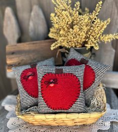 three red hearts on black and white checkered pillows in a basket with yellow flowers