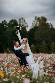 a bride and groom are in a field full of wildflowers holding each other