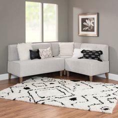 a white rug with black and white pillows on it in front of a gray couch