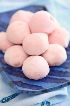 a blue plate filled with pink colored donuts on top of a white table cloth