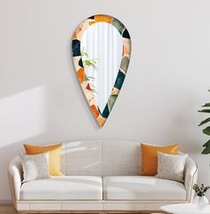 a living room with a couch, mirror and potted plant on the wall in front of it