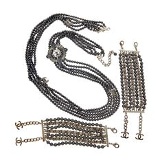 This is a very rare and magnificent Chanel Parure with a 38 inch Chanel CC Multistrand Black Faux Pearl and Rhinestone Necklace and Two Bracelets with the original 2 Chanel pouches and box. The statement necklace and bracelets feature faux Black Pearls, Colorless and gray rhinestones, and 'CC' charms. The bracelets are designed with woven through leather chains. Provenance: The Estate of a Park Avenue Lady The bracelets are 6 inches in length. They are 2 inches wide. The necklace is 38 inches lo Chanel Pouch, Bracelet Box, Rhinestone Necklace, Leather Chain, Multi Strand Necklace, Black Pearl, Multi Strand, Faux Pearl, Statement Necklace