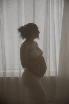 a pregnant woman standing in front of a window