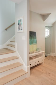 there is a painting on the wall next to some drawers in this room with stairs