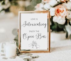 an open bar sign sitting on top of a table next to a vase filled with flowers