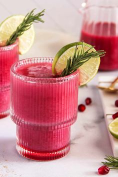 two glasses filled with cranberry lemonade and garnished with rosemary on the rim