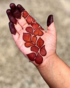 a person's hand with red and brown designs on their palm, which is holding something in the air