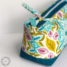 a small blue and yellow flowered bag on a white surface with the zipper undone