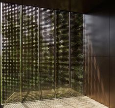 an empty bench in front of a wall with perfored panels on it's sides