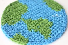 a crocheted blue and green dishcloth on a white surface with the earth in it