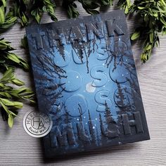 a book sitting on top of a wooden table next to some leaves and branches in front of it