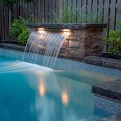 a small pool with a waterfall in the middle and lights on it's sides