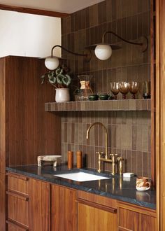 a kitchen with wooden cabinets and marble counter tops, along with brass faucets