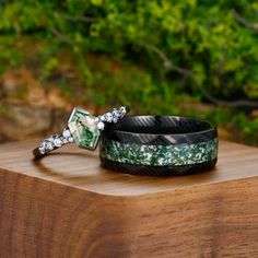 two bracelets sitting on top of a wooden table in front of some green plants