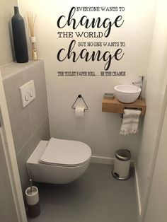 a bathroom with a toilet, sink and wall decal that says everyone wants to change the world but no one wants to change