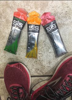 the shoes are lined up on the floor next to three bars of sports nutrition product