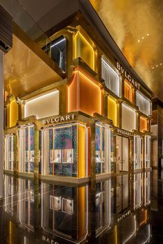 the interior of a luxury shopping mall with gold and red accents on the walls, along with mirrored flooring