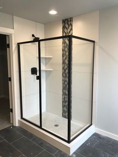 a walk in shower sitting inside of a bathroom next to a wall mounted shelf and door