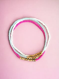 three beaded bracelets on a pink background