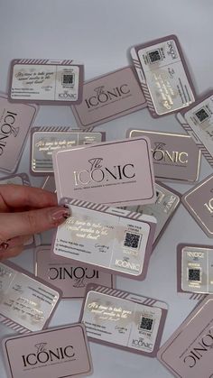 a person holding up some pink and silver business cards with the word iconic on them